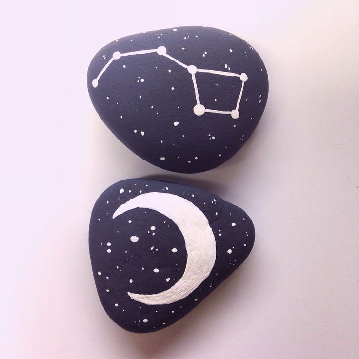 two rocks with the moon and stars painted on them are sitting next to each other