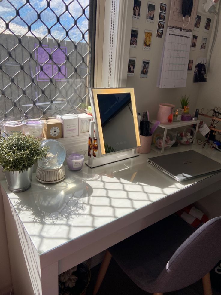 a white desk with a laptop computer sitting on top of it next to a window