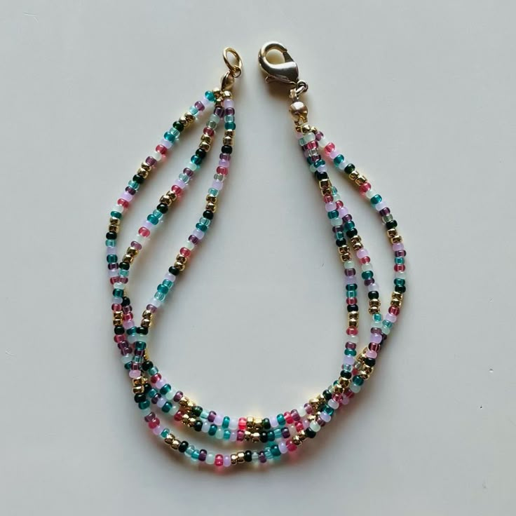 multicolored beaded necklace with gold clasp on white background, close up view