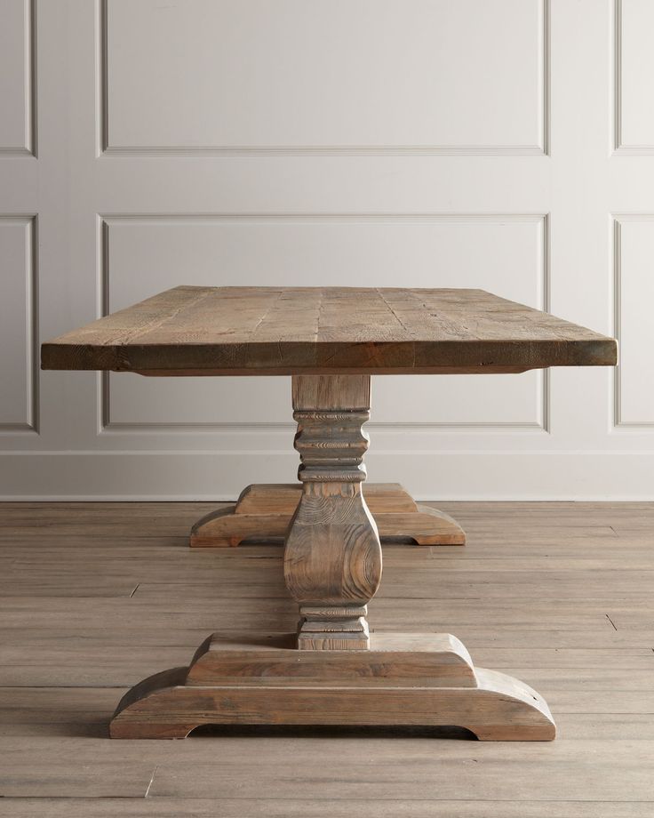 a wooden table sitting on top of a hard wood floor next to a white wall