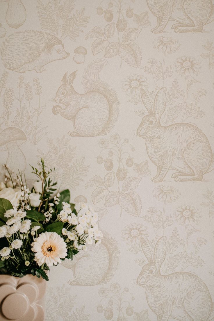 a vase filled with white flowers sitting on top of a table next to a wall