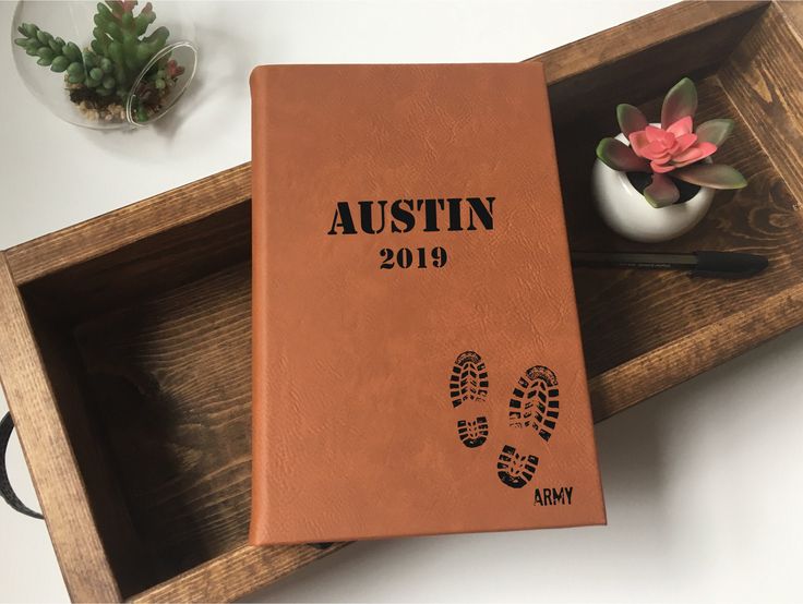 an orange leather book with imprints on the cover is sitting in a wooden tray