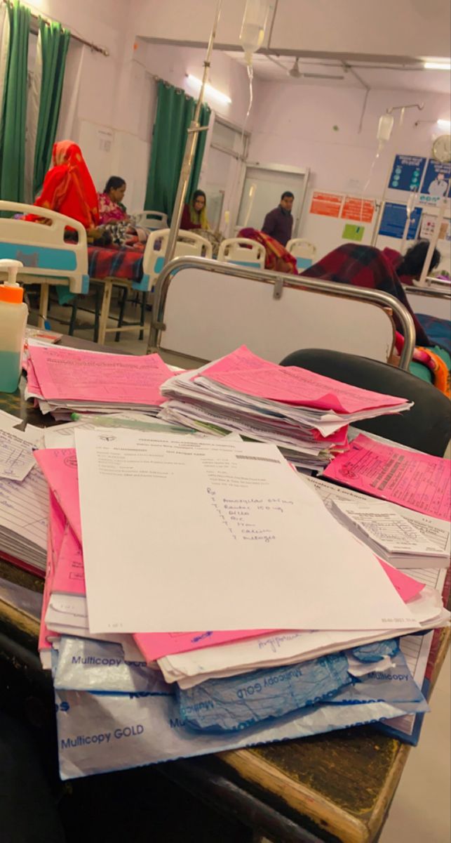 many papers are piled on top of each other in a room with people sitting at tables