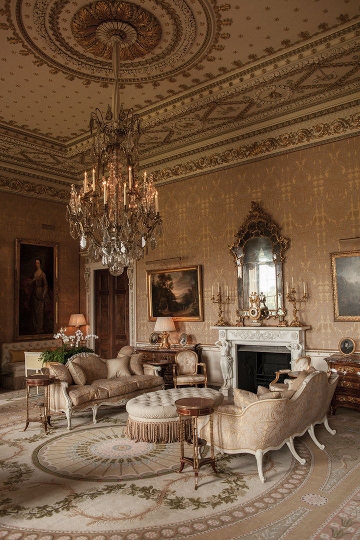 an ornate living room with chandelier, couches and two chairs in it