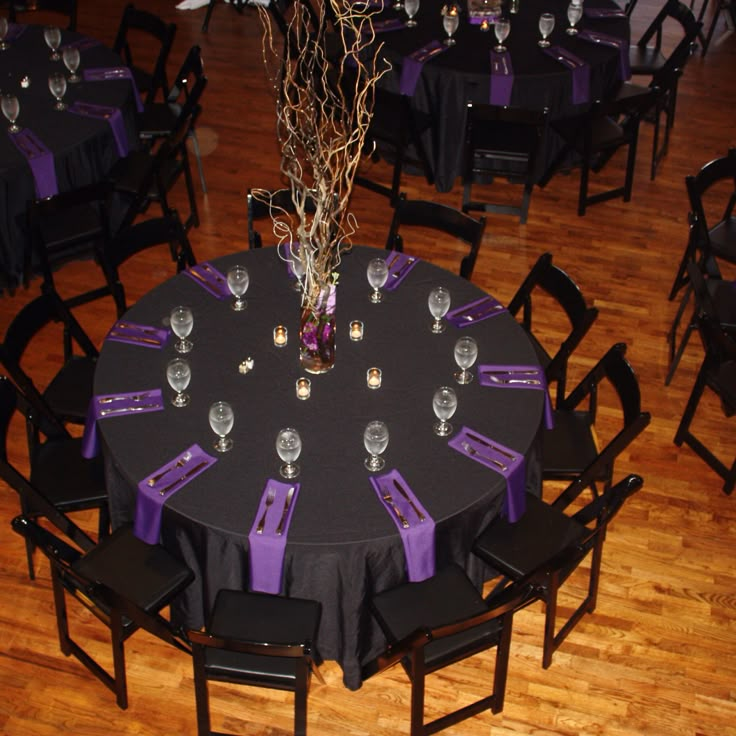 the table is set up with purple napkins and place settings for guests to sit at