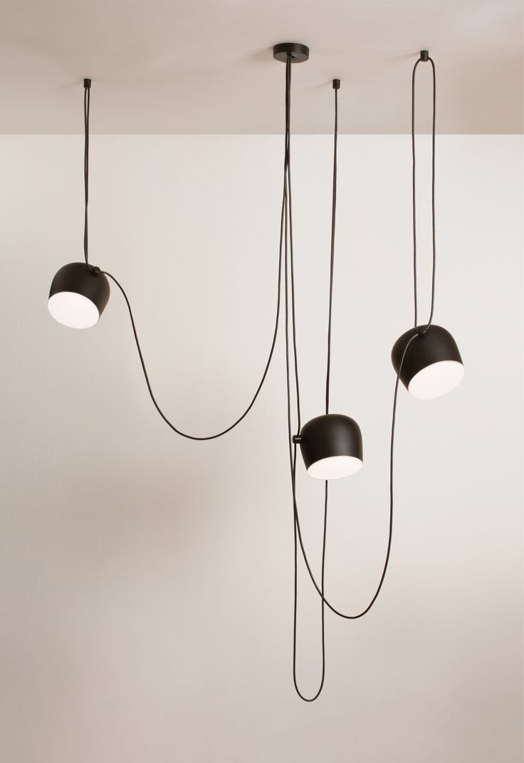 three black lamps hanging from the ceiling in a room with white walls and flooring