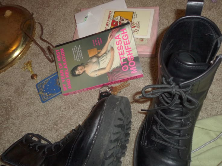 there is a pair of black boots on the floor next to books and other items