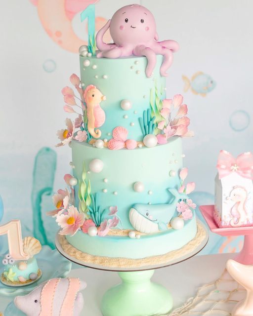 there is a blue cake decorated with an octopus and sea animals on the top tier