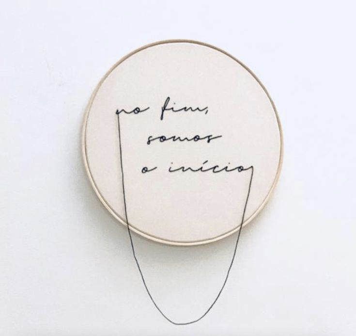 a handwritten quote on a white wall hanging from a hoop with black thread in it