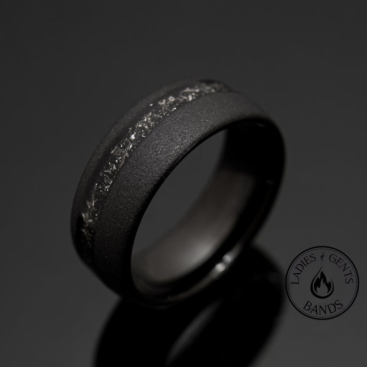 a black ring with silver glitters on the outside and inside, against a dark background