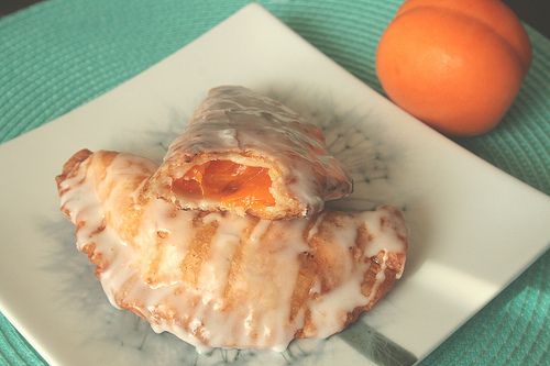 a plate with two pastries on it next to an orange