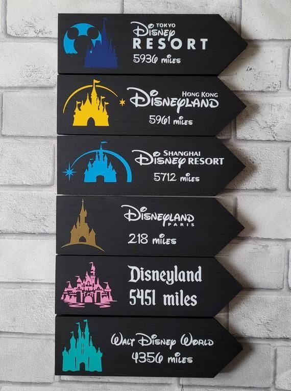 three wooden signs with disney world and disneyland parks on them hanging from a brick wall