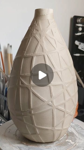 a white vase sitting on top of a table next to markers and pencils in front of it