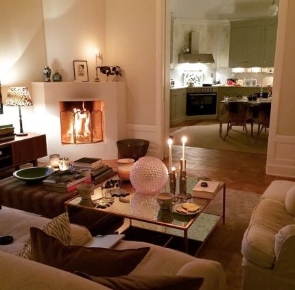 a living room filled with furniture and a fire place next to a table covered in candles