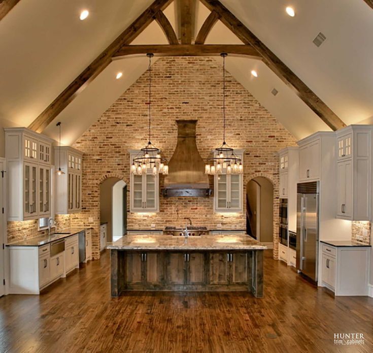 a large kitchen with wooden floors and an island in the middle, surrounded by white cabinets