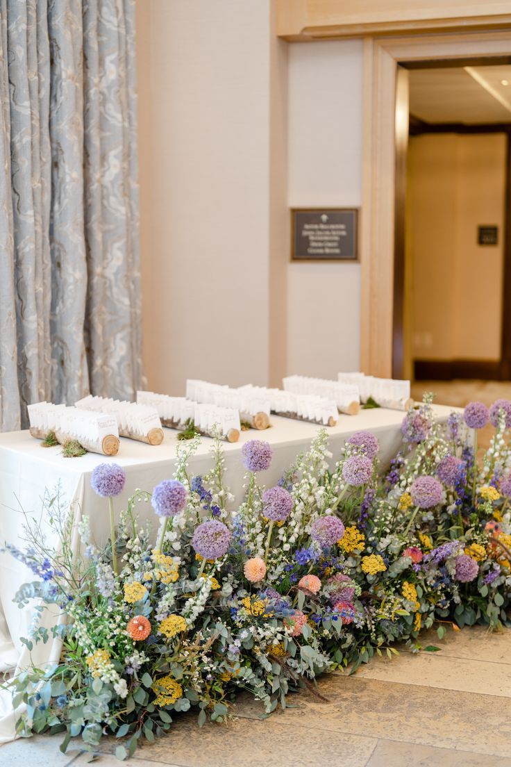 the table is set up with flowers and place cards on it for guests to sign