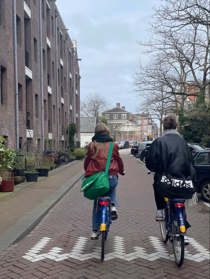 two people riding bikes down a brick street