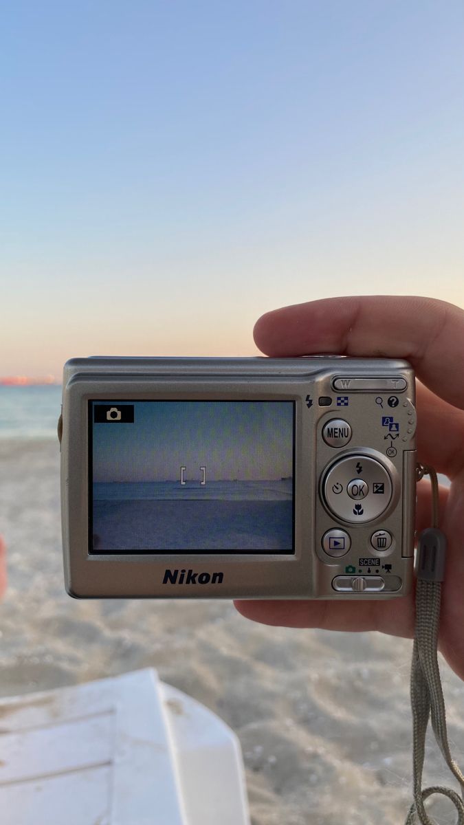 a person holding up a camera on the beach