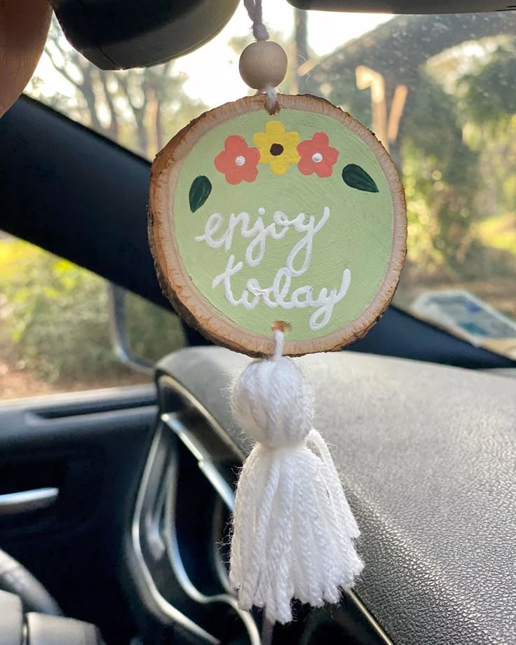 a car dashboard decoration with the words enjoy it's friday hanging from a steering wheel