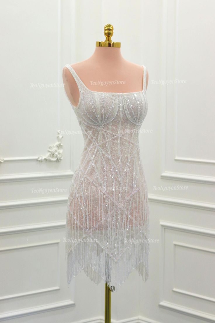 a mannequin dressed in white sequins and beaded dress on display