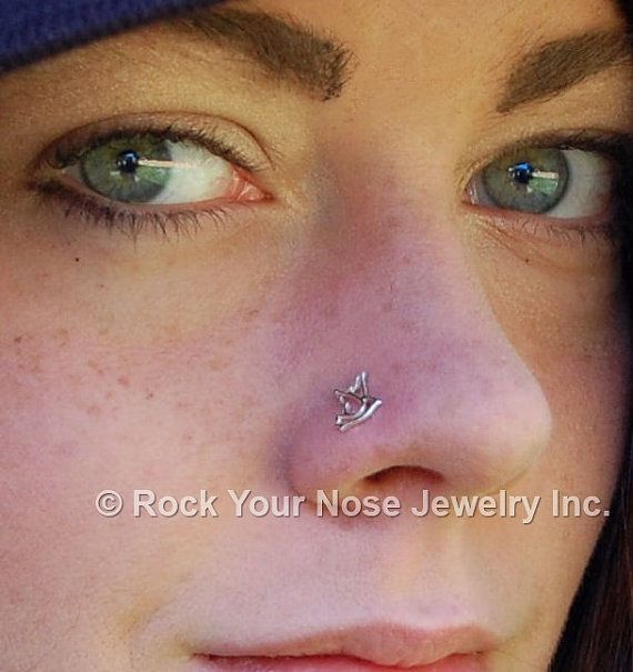 a close up of a woman with a nose piercing on her nose and wearing a beanie hat