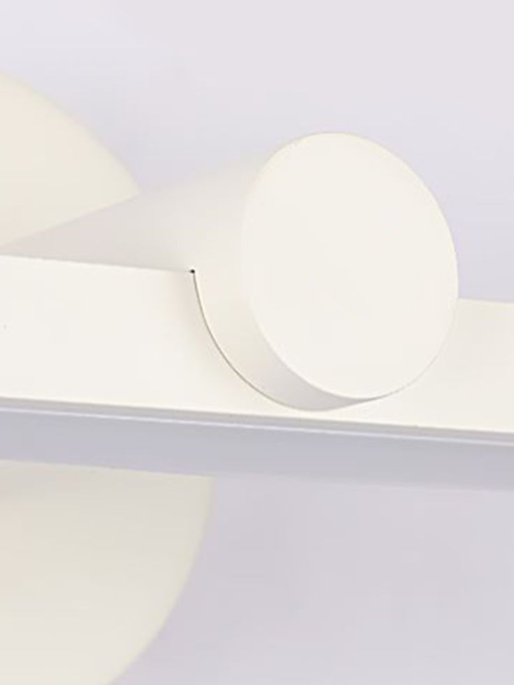 a white shelf with two round knobs on it's sides and a circular object in the middle