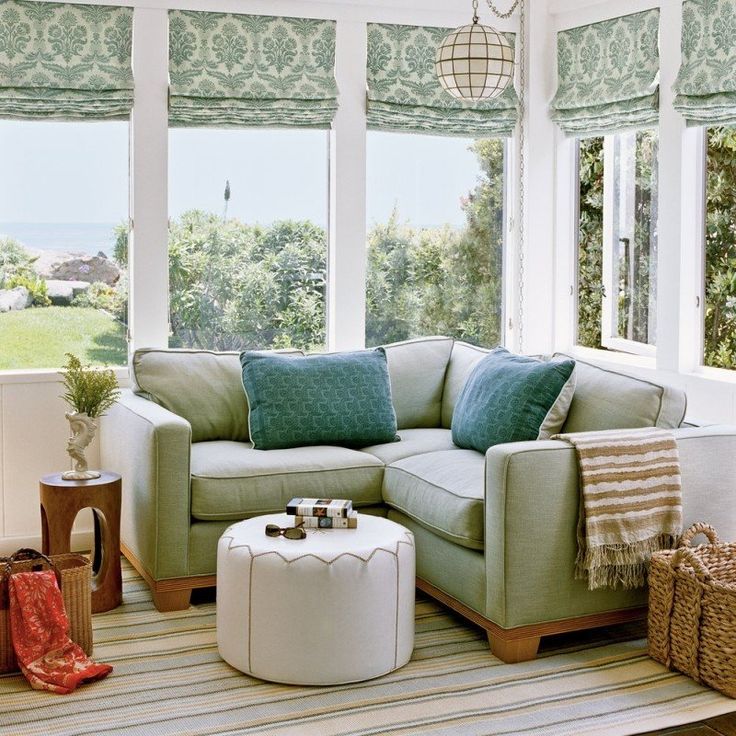 a living room with a couch, ottoman and windows