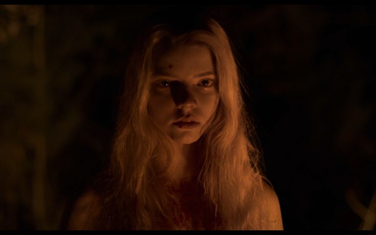 a woman with long blonde hair standing in the dark