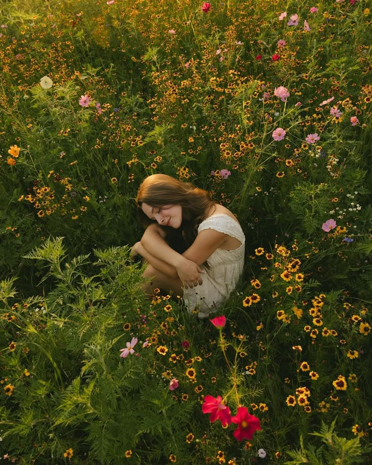 a woman sitting in the middle of a field of flowers