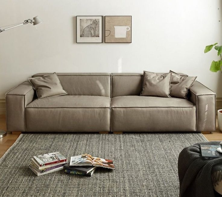 a living room filled with furniture and pillows on top of a gray rug next to a window