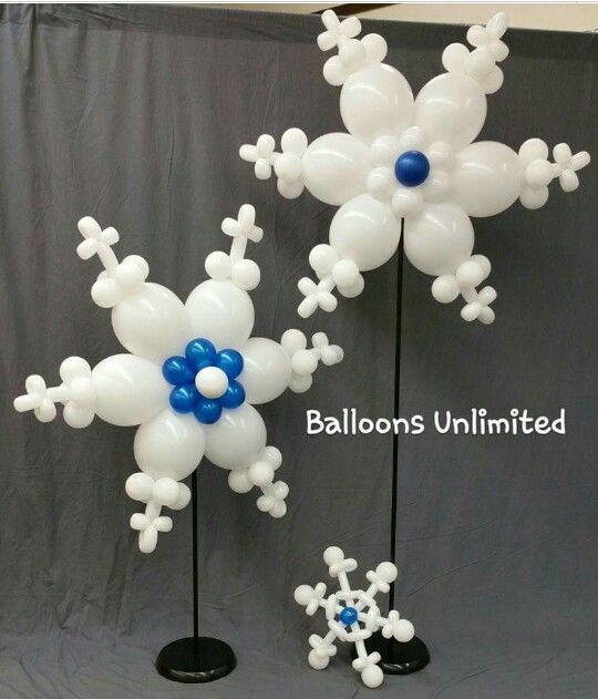 balloon snowflakes are on display in front of a gray backdrop with white and blue decorations