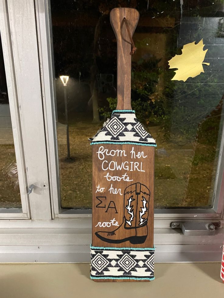 a wooden sign with writing on it sitting in front of a window sill next to a flag