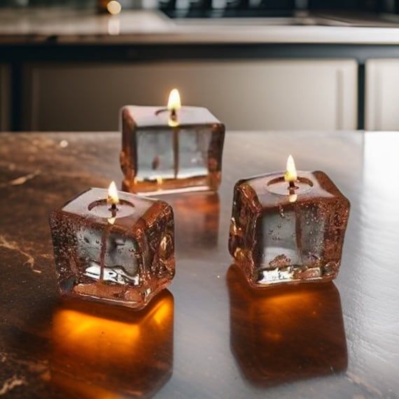 three lit candles sitting on top of a table next to each other with ice cubes in the middle