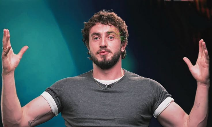 a man standing in front of a blue background with his hands up to the side