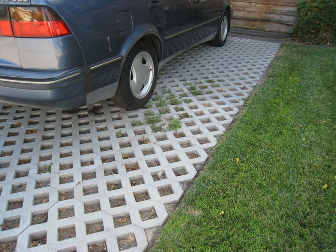 a blue car parked in front of a wooden fence next to a green grass covered yard