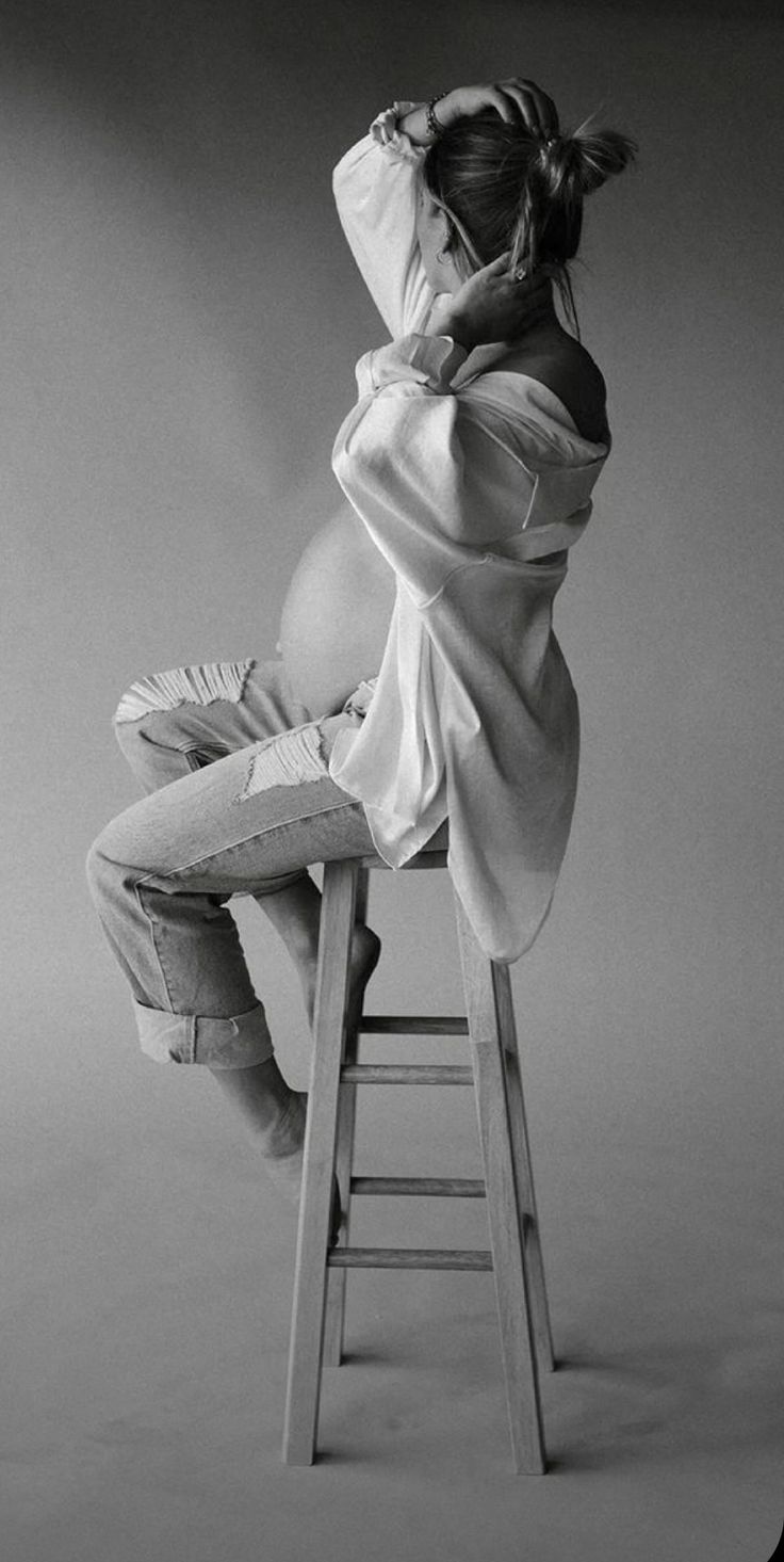 a woman sitting on top of a wooden stool