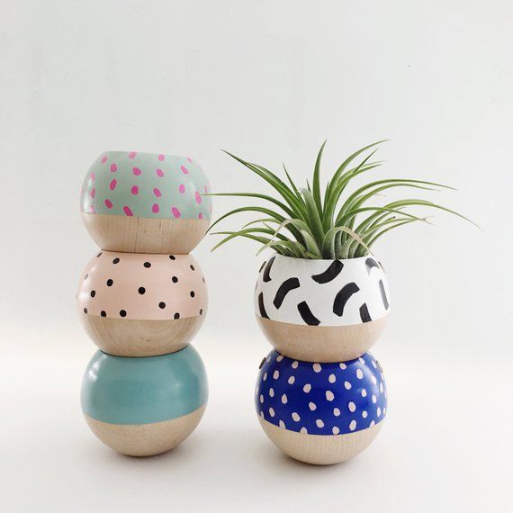 three ceramic pots with plants in them on a white surface, one is painted blue and the other has polka dots