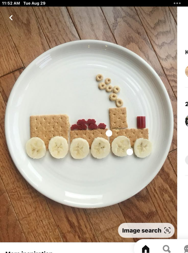 a white plate topped with crackers and bananas on top of a wooden table next to an image of a train