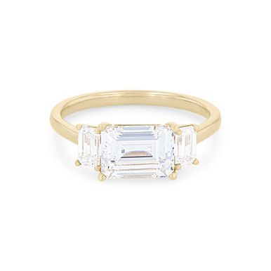 an emerald and diamond three stone ring in yellow gold, set on a white background