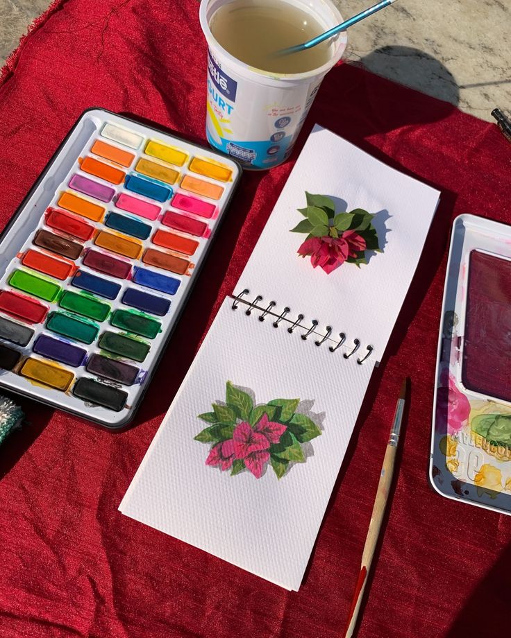 the table is set up with paints, paper and watercolor pencils on it