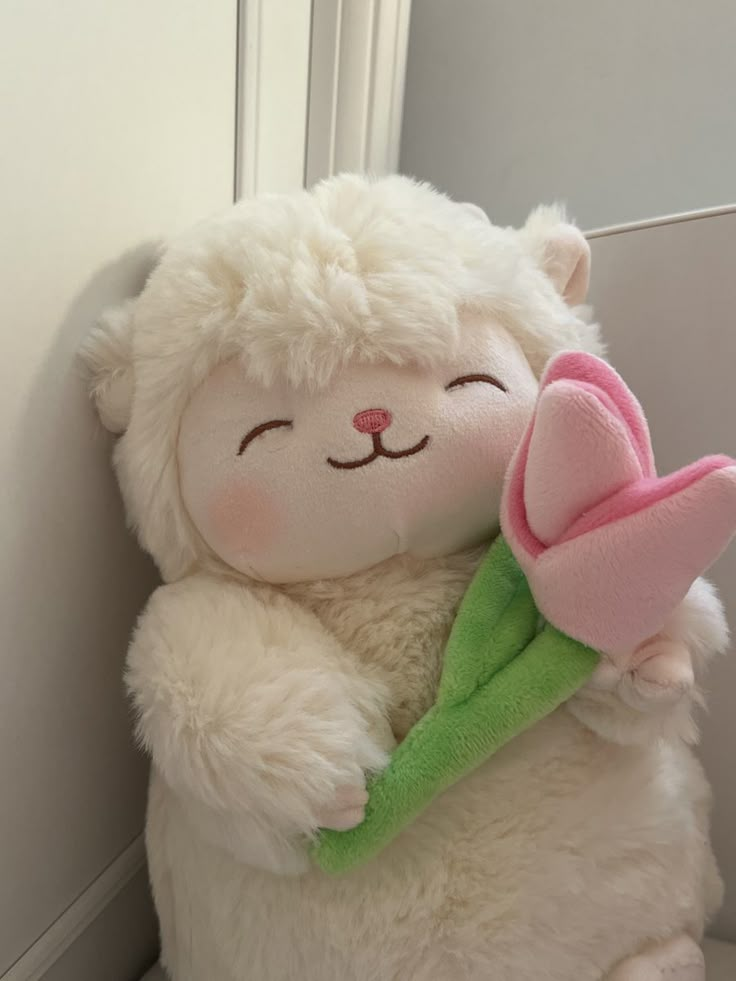 a white stuffed bear holding a pink flower