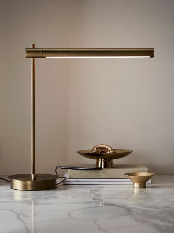 a table lamp sitting on top of a white counter next to a plate and bowl