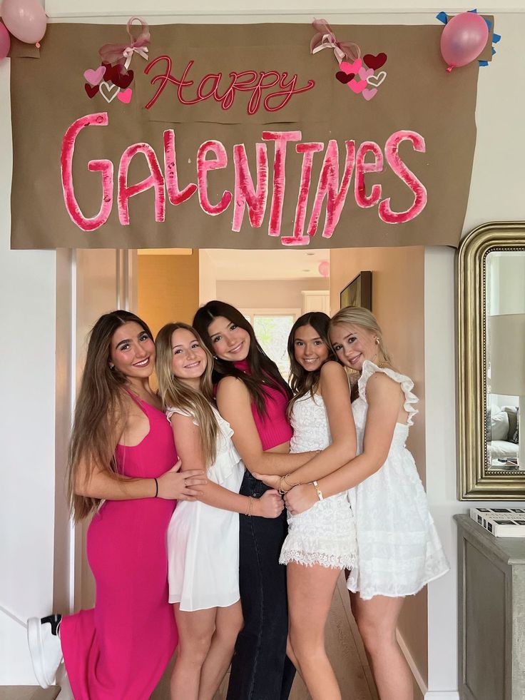 four girls posing in front of a happy valentine's day sign