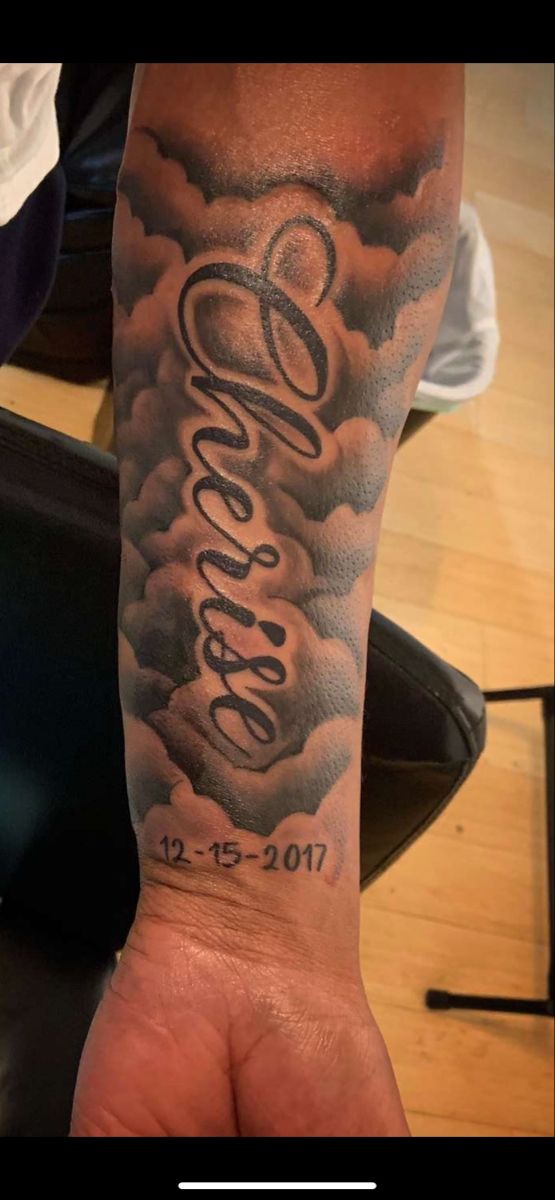 a man's arm with clouds and lettering on it