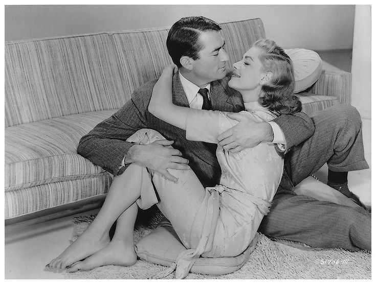 a man and woman sitting on the floor next to a couch with their arms around each other