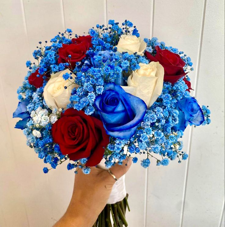 a person holding a bouquet of red, white and blue flowers