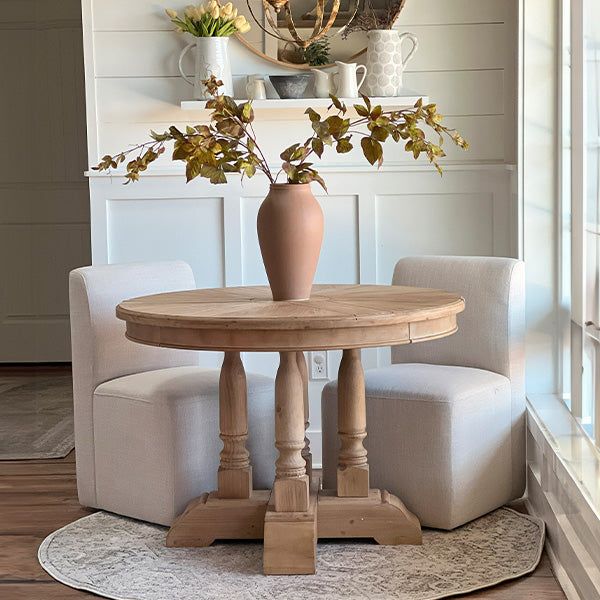 a table with two chairs and a vase on it in the middle of a room