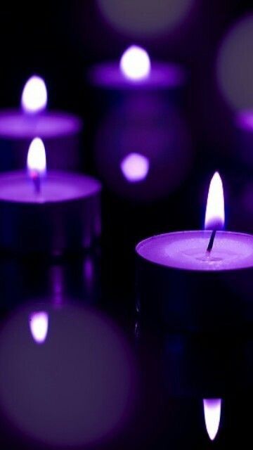 many lit candles with purple lights in the background