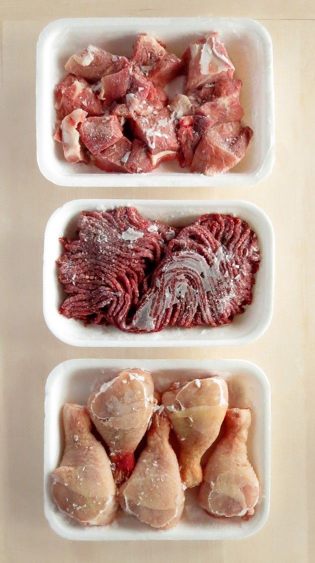 three bowls filled with meat on top of a wooden table