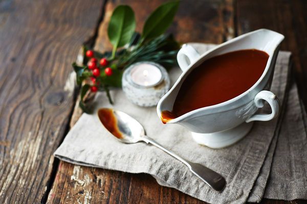 a white gravy dish and spoons on a napkin with holly sprig